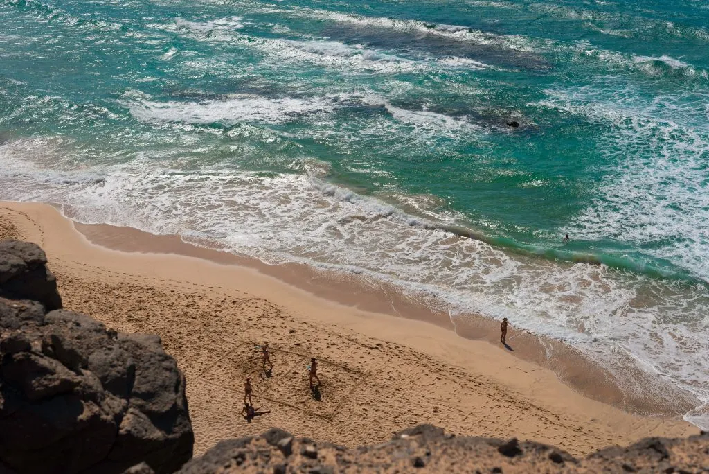 view of people walking on the sandy beach at el cotillo, one of the best spanish seaside towns