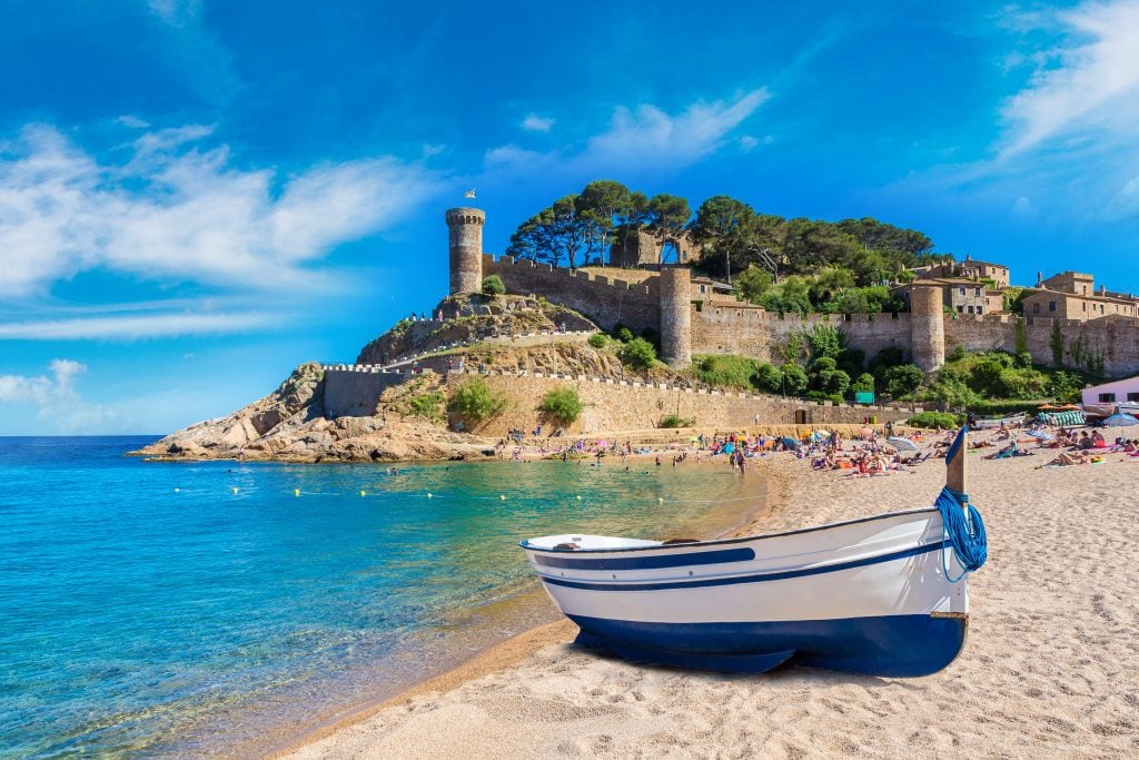 beautiful spain beach on costa brava with boat in the foreground and castle in the background, tossa de mar
