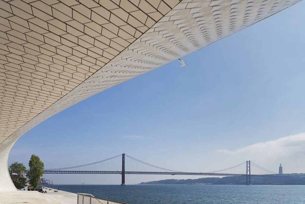 exterior of the maat museum with the ponte 25 abril bridge and tagus river in the background, one of the best things to do in lisbon winter