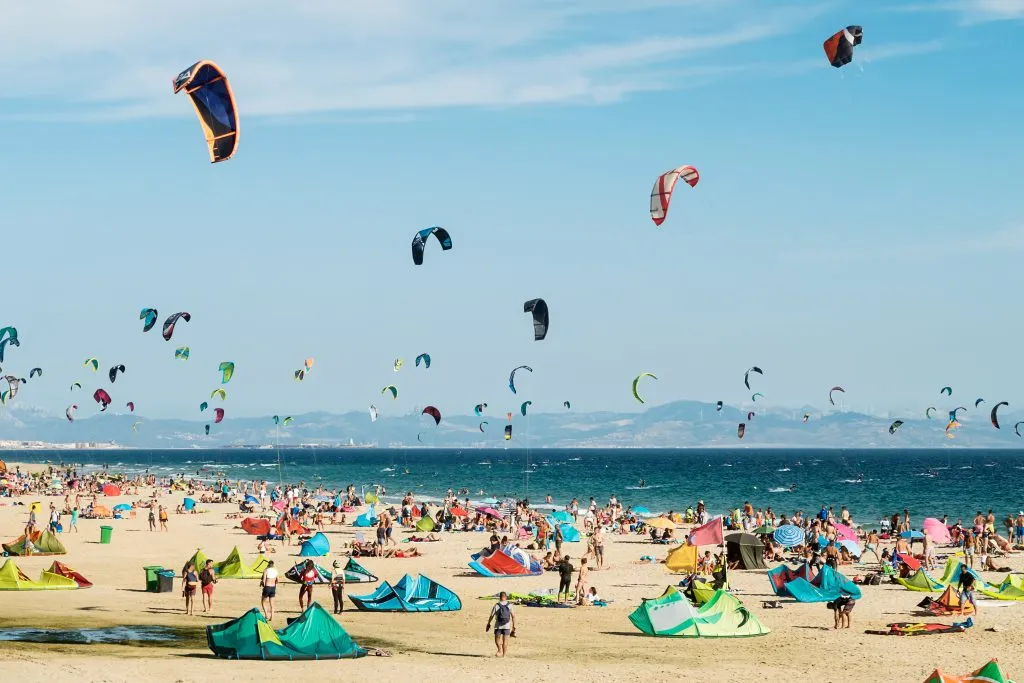 crowded beach in tarifa with kites in the air, one of the best beach towns in spain