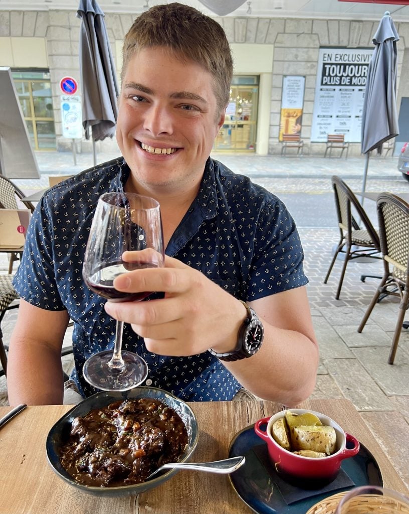 jeremy storm holding a glass of burgundy wine with dinner when visiting dijon france