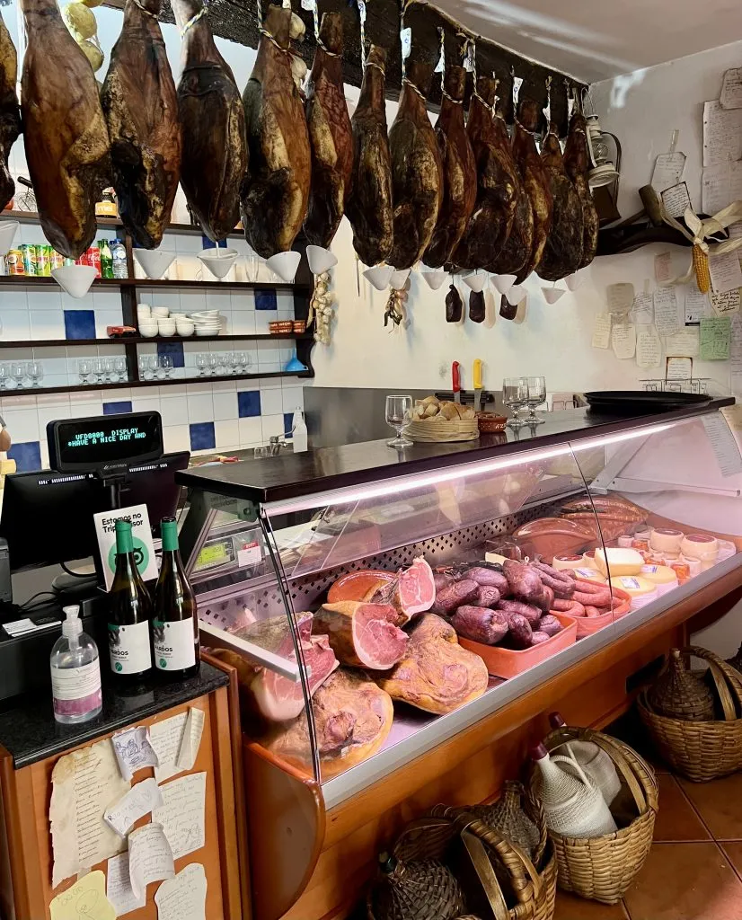 counter of taberna don rodrigo restaurant amarante portugal with hams hanging from ceiling