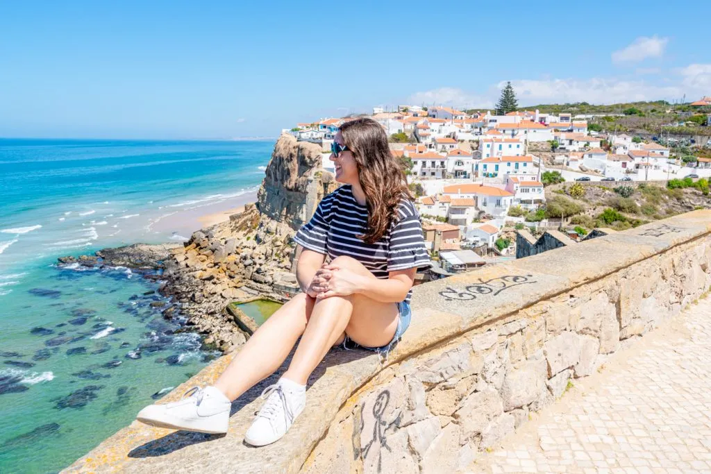 kate storm sitting on a wall overlooking azenhos do mar in central portugal