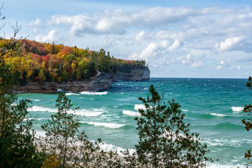 view of fall foliage with lake in the foreground on michigan upper peninsula