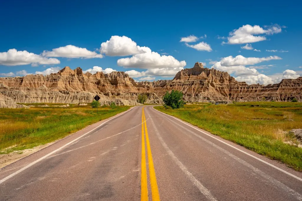 straight 2 lane road leading through the landscape of badlands national park, one of the best road trips midwest usa