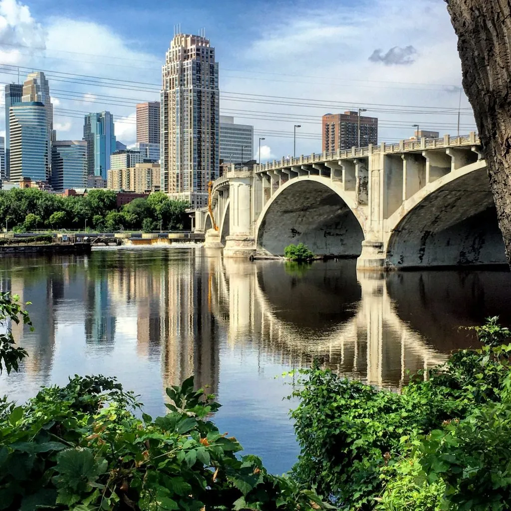 minneapolis skyline with stone arch bridge in the foreground, one of the best midwestern road trip stops