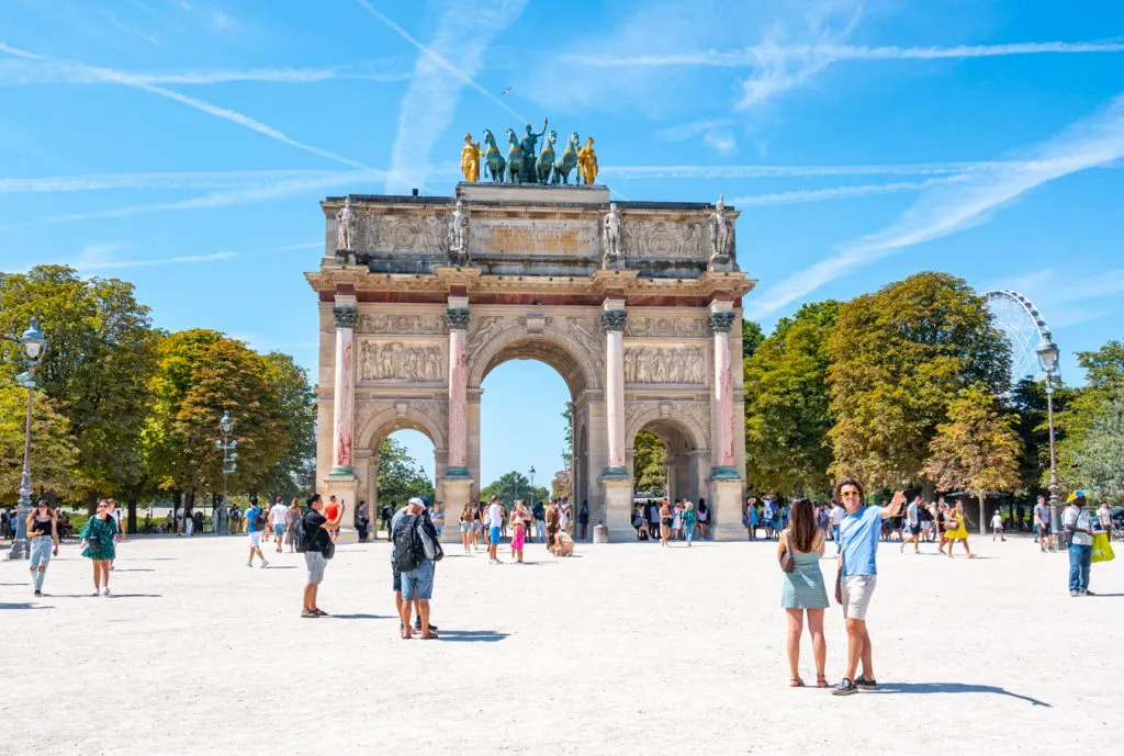 travelers standing in front of arch near the louvre, a fun spot to visit when planning a trip to paris france