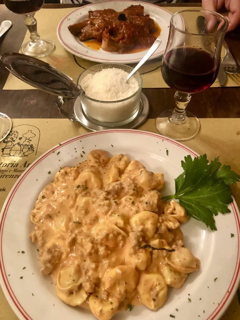 pasta dish with meat dish in the background as enjoyed when eating in italy