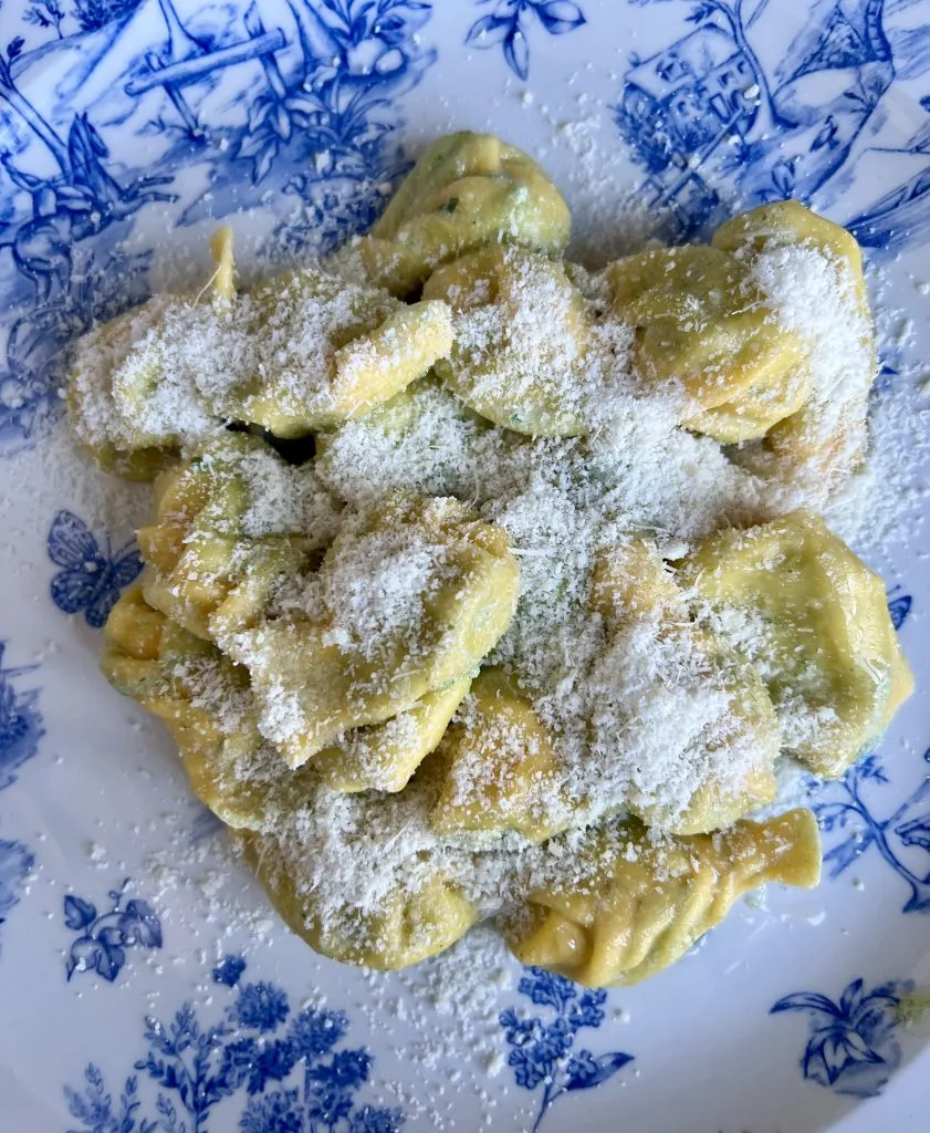 tortelli dusted with cheese on a white and blue plate