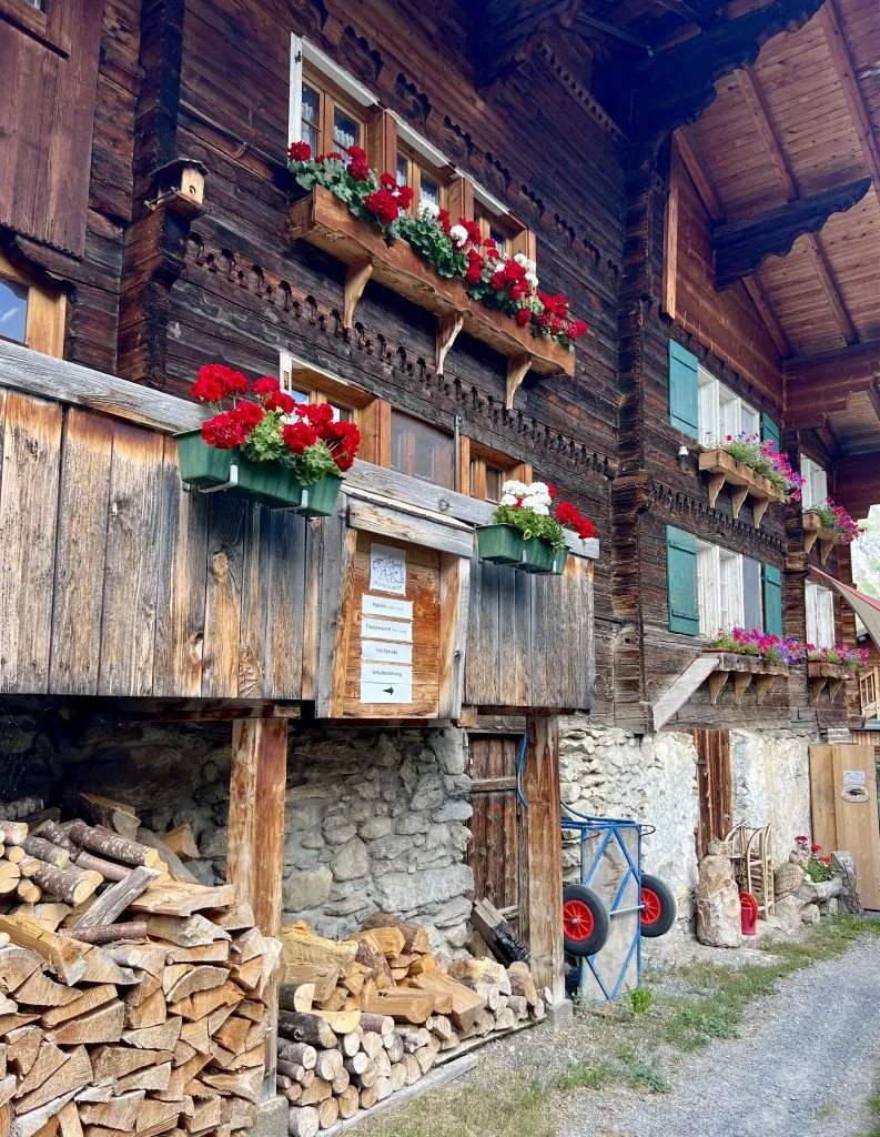 colorful flower boxes and chopped wood set against a classic swiss chalet, best places to visit in gimmelwald switzerland