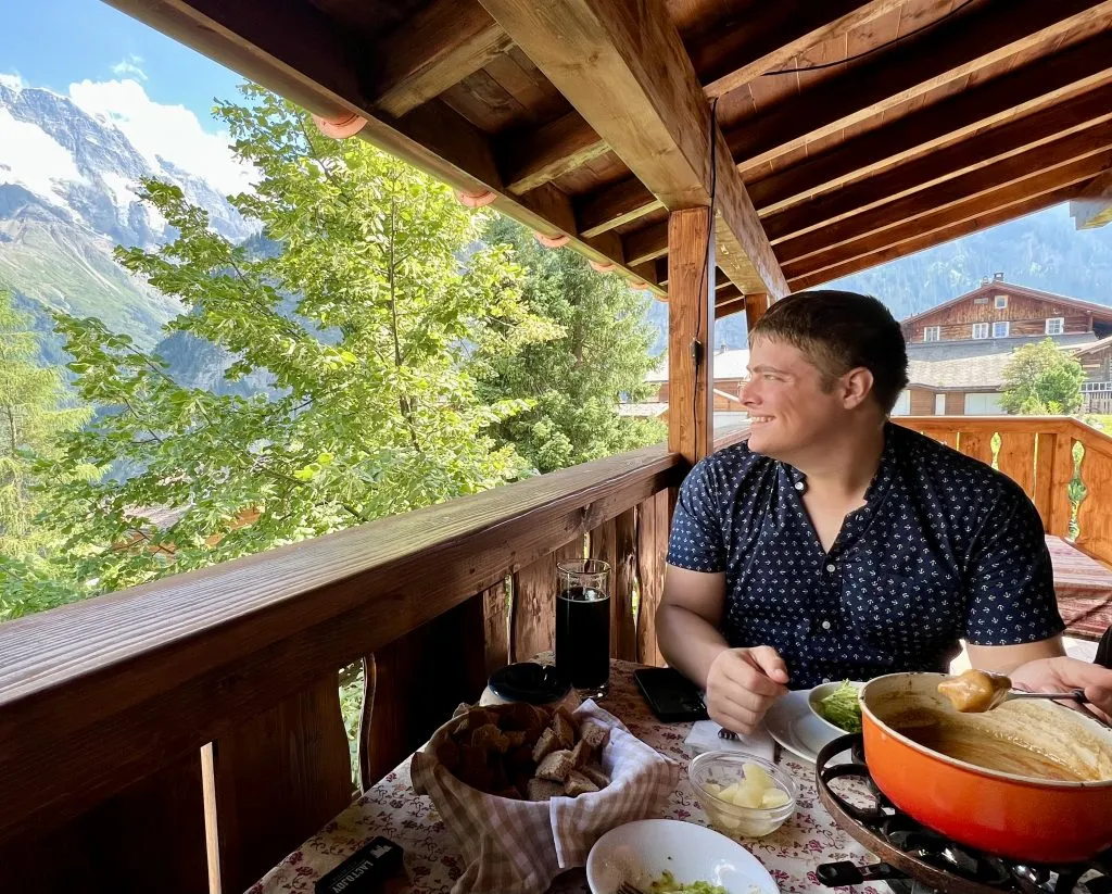 jeremy storm eating fondue at mountain hostel gimmelwald overlooking the alps