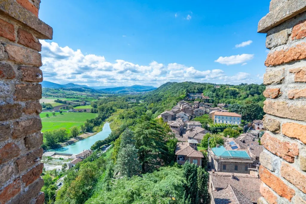 view of castle arquato and river po framed by the walls of a castle tower