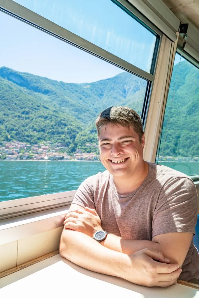 jeremy storm sitting near the window of a ferry from bellagio to varenna on lake como