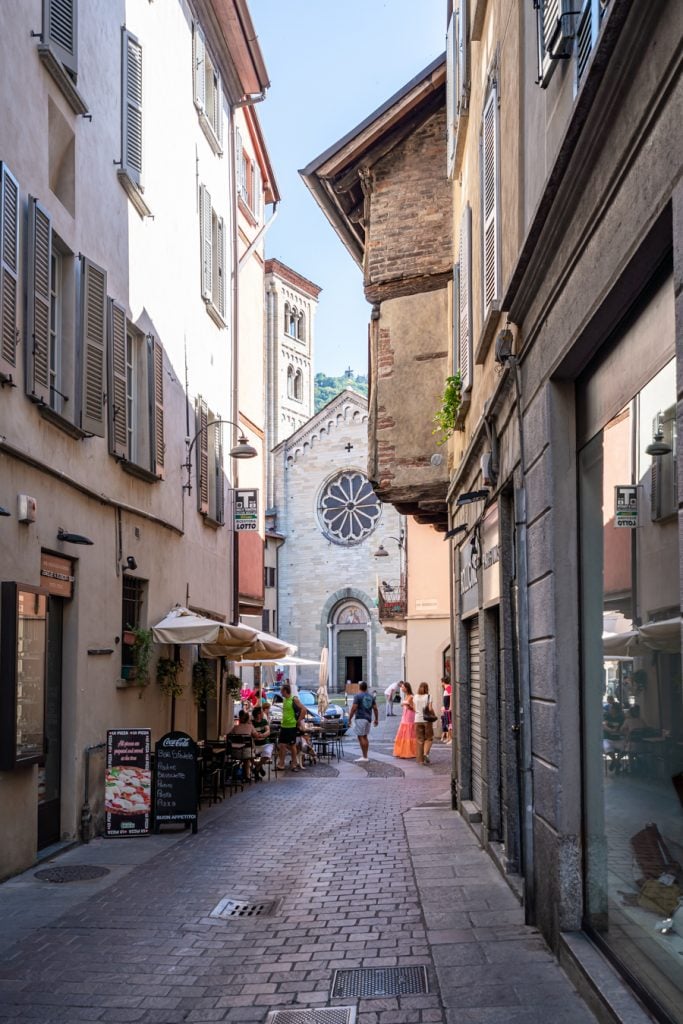 downtown como italy with church visible at the end of a small street