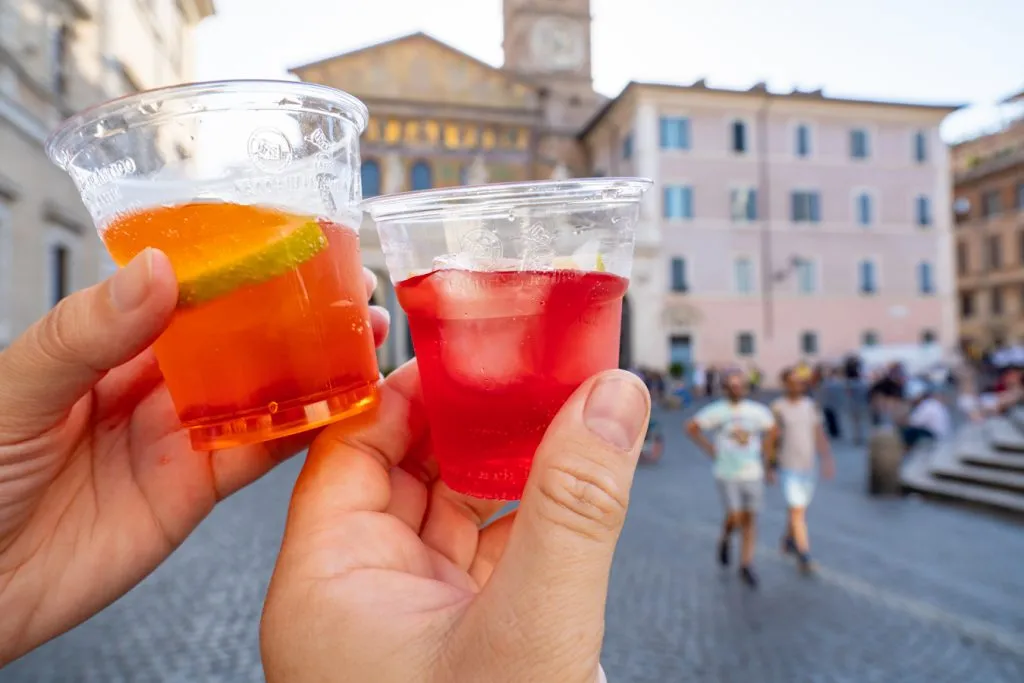 hands holding up aperol spritzes in trastevere italy on a trastevere food tour
