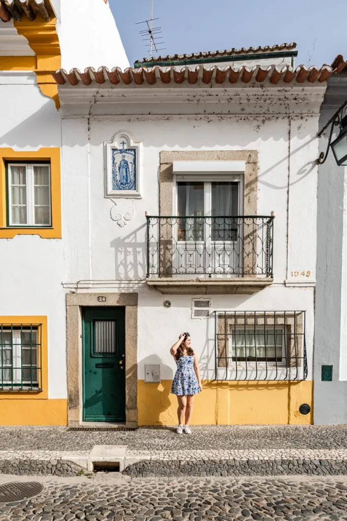 kate storm standing in front of a white building with yellow trim when visiting evora activities