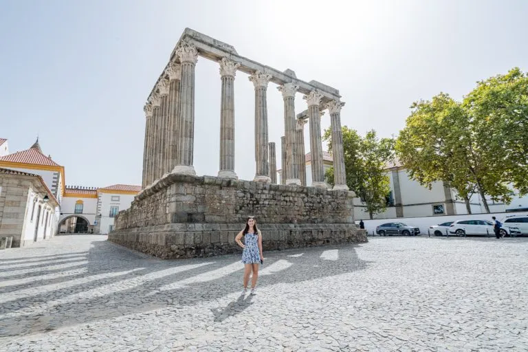 kate storm standing in front of roman temple of diana, one of the best things to do in evora portugal