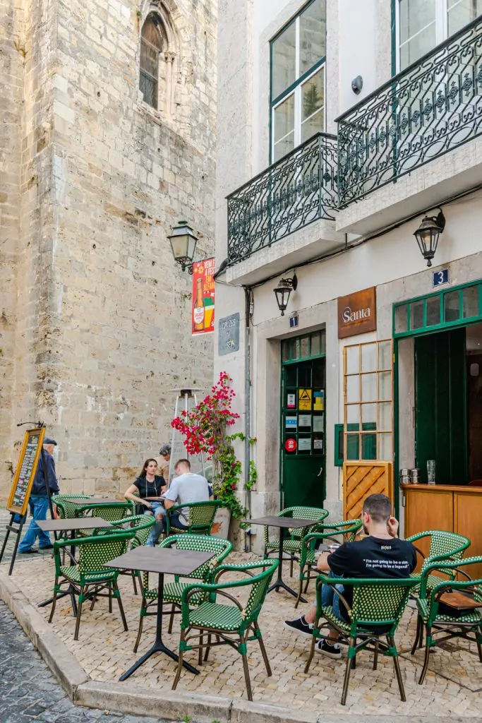cafe in alfama lisbon with the wall of the cathedral in the background