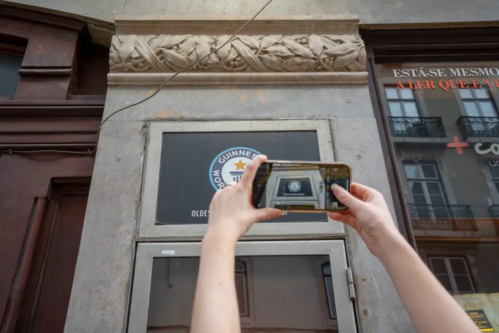 person taking an iphone photo of the guinness book of world records sign for the worlds oldest bookstore lisbon