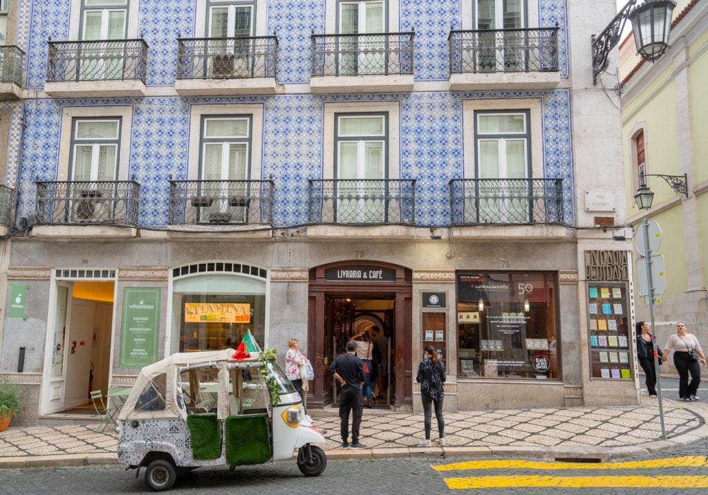 front facade of livraria bertrand lisbon chiado, with tuk tuk parked out front