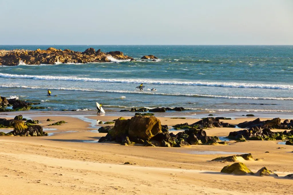 rocky beach in matosinhos portugal with surfers on it, one of the best coastal towns in portugal to visit