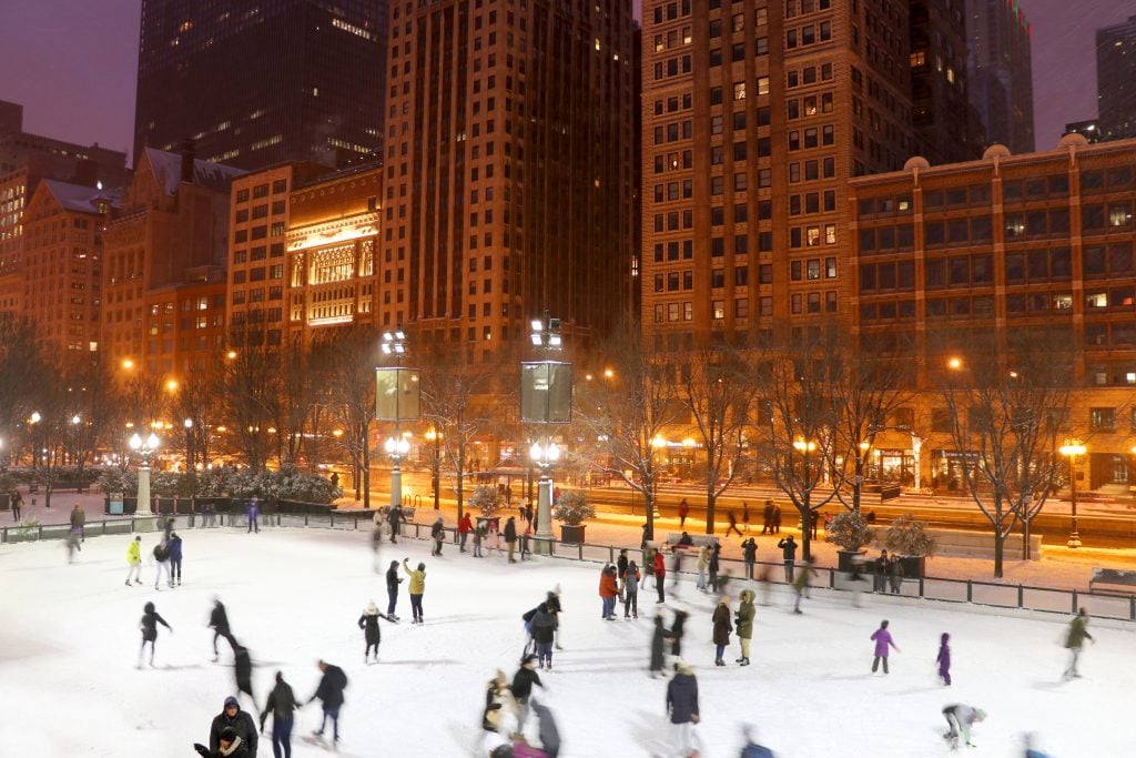 people ice skating in downtown chicago at night, one of the best places to visit in winter in usa