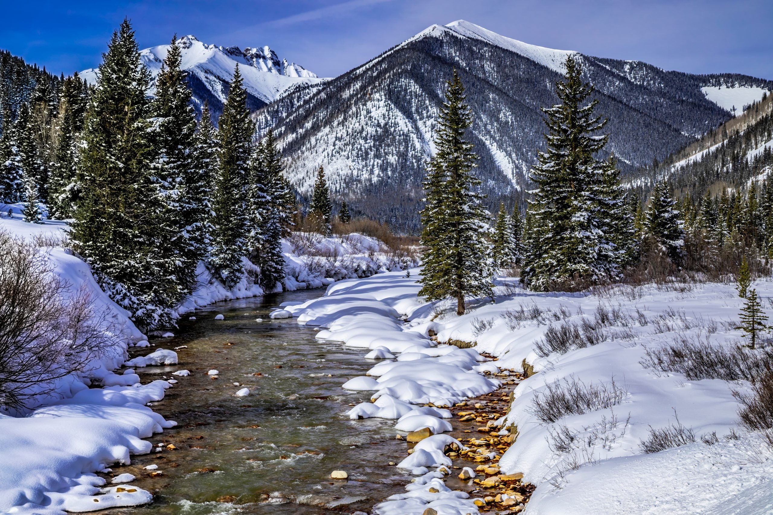 winter landscape in colorado mountains with river in the foreground, one of the best winter vacations in usa