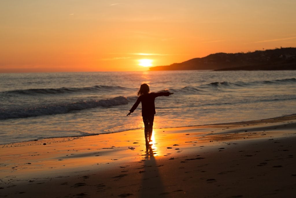 child on the beach at sunset in praia da luz, one of the best beach towns in portugal to visit