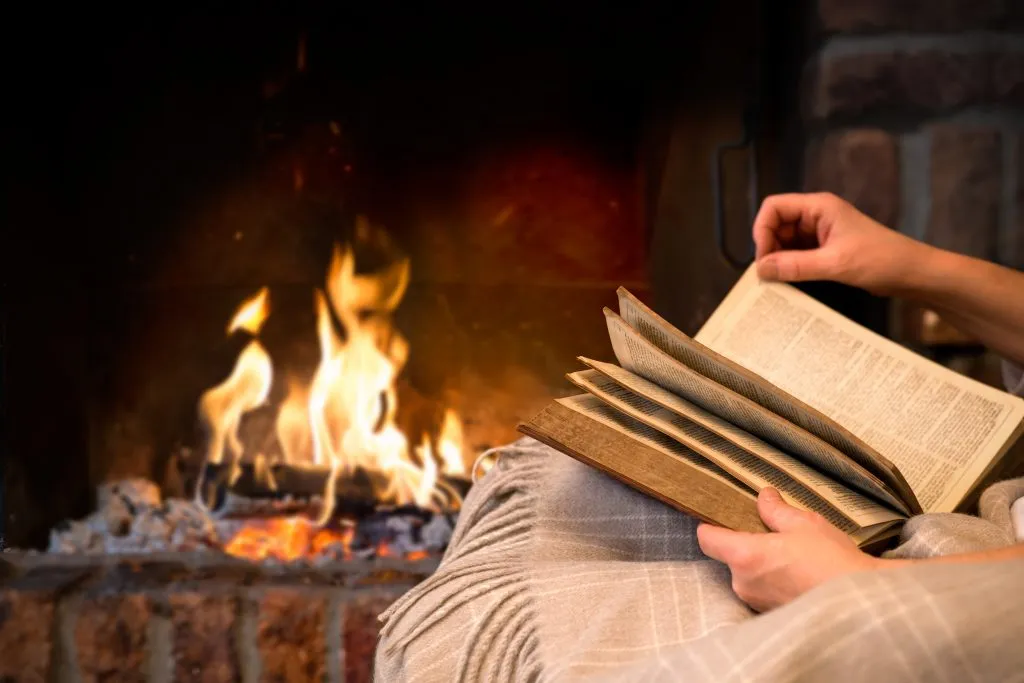close up of someone reading a book in front of a fire during one of the best winter vacations in the us