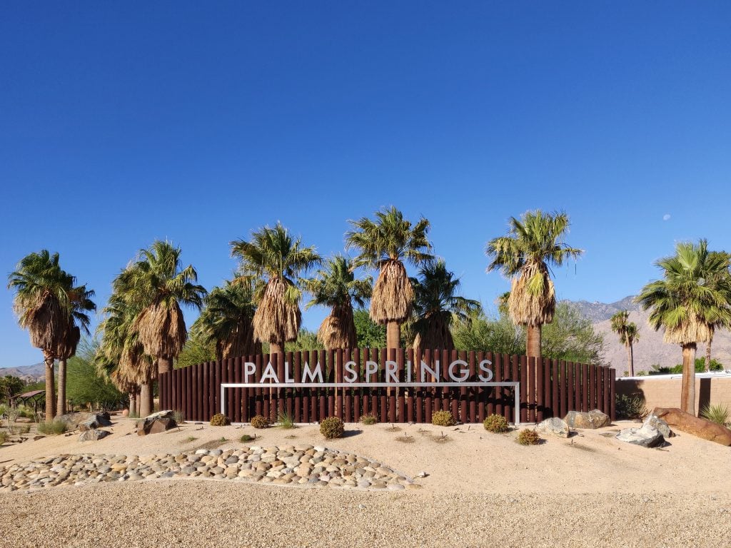 sign with white lettering reading "palm springs" at entrance to california town