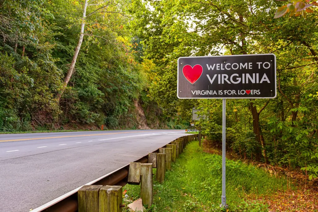 sign reading "welcome to virginia" along a forested road, a common sight when en route to the best virginia vacation spots