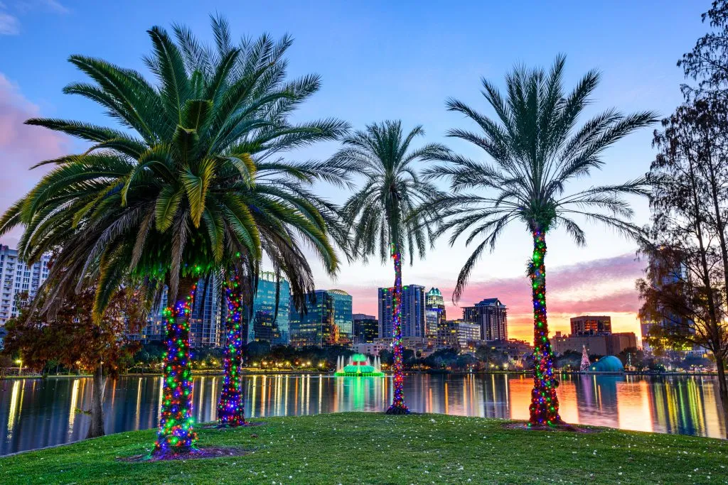 sunset at lake eola in orlando florida with palm trees in the foreground decorated for christmas