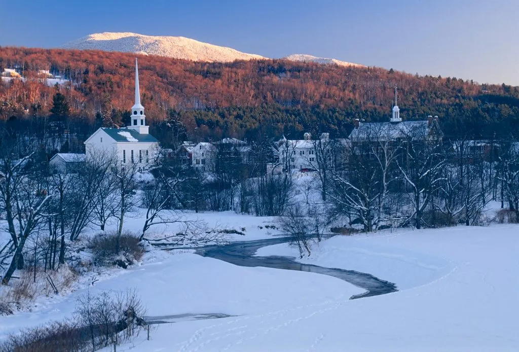 stowe vermont in winter at sunset with snow in the foreground