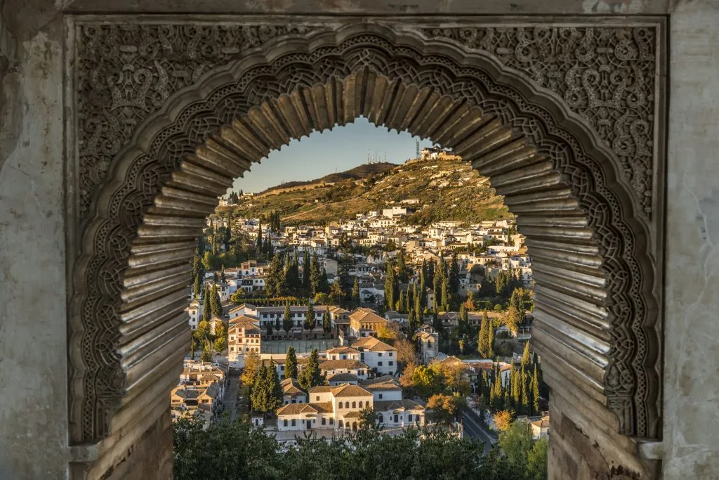 view of granada through an intricate window in the alhambra tips