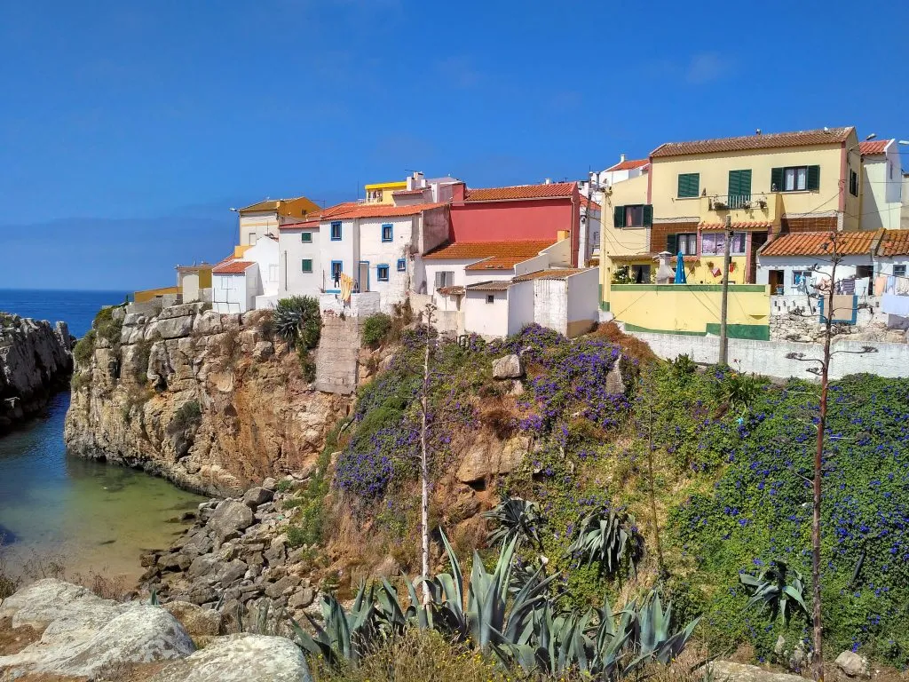 colorful houses perched on a cliff in peniche, one of the top beach towns portugal