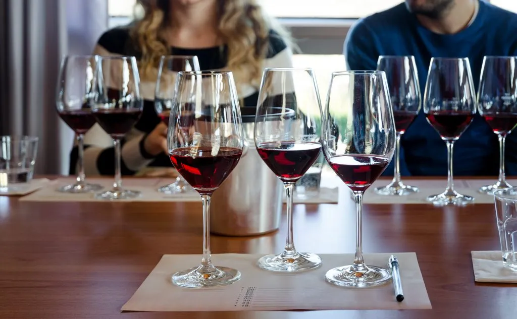 several glasses of wine set out on a wood table at a wine tasting