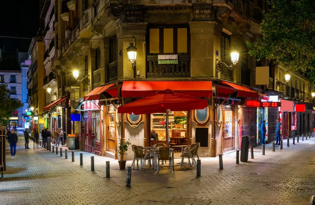 cafe in madrid spain at night with red awnings, visiting tapas bars is one of the best things to do in madrid at night