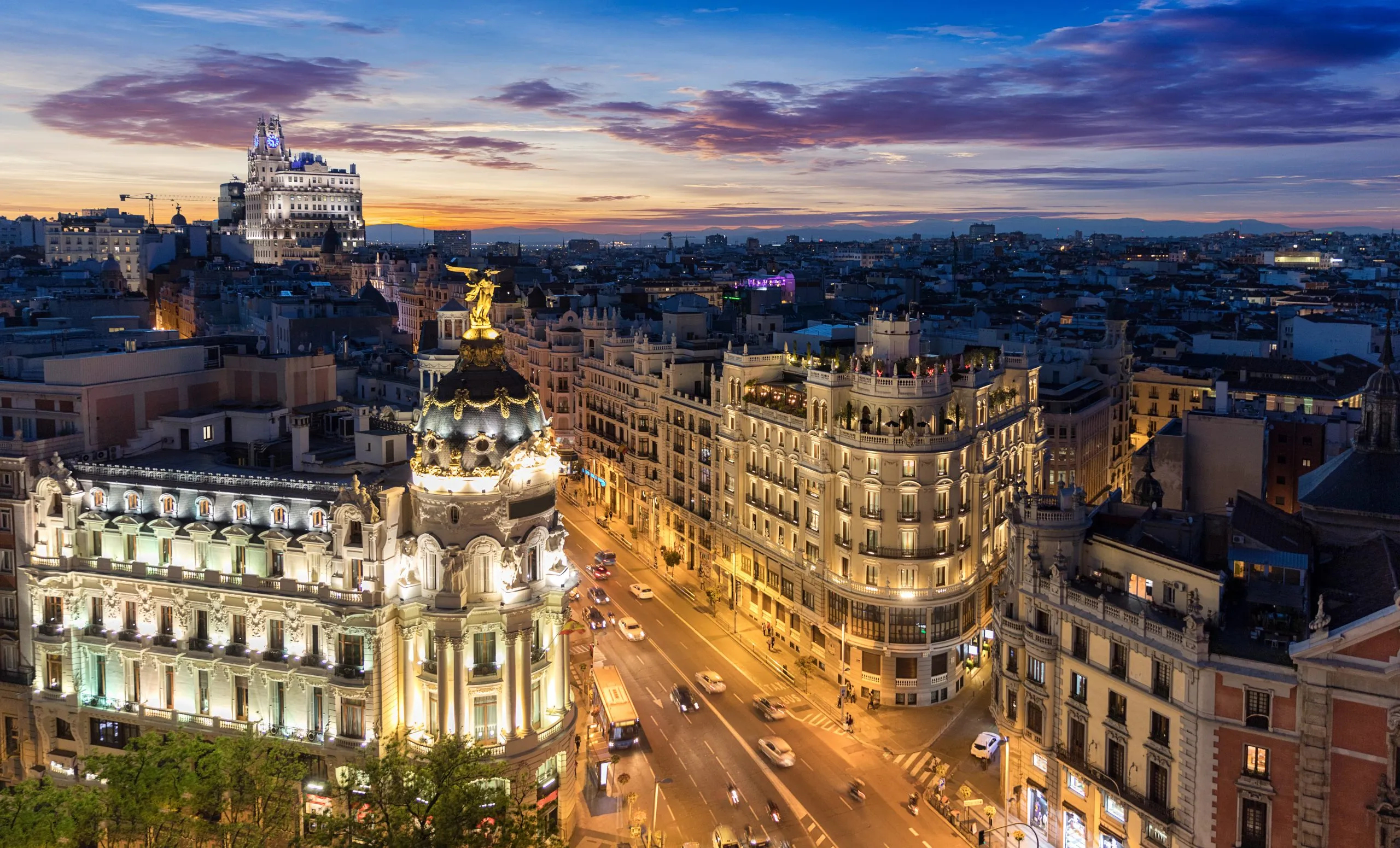 view of skyline of madrid at night with metropolitan building seen from rooftop
