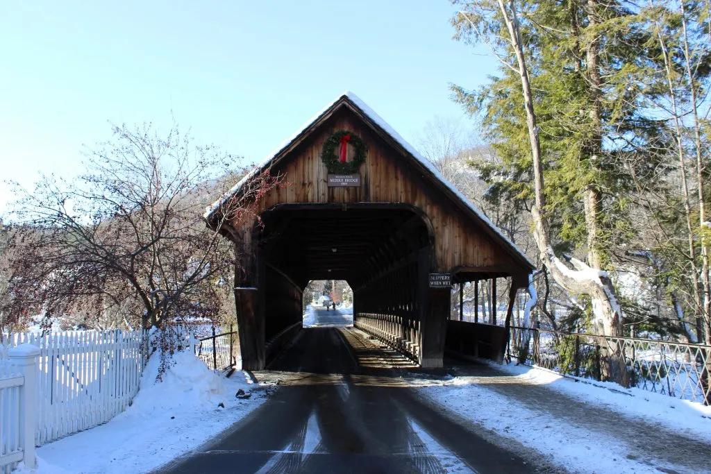 middle covered bridge in woodstock vermont in winter with a christmas wreath on it