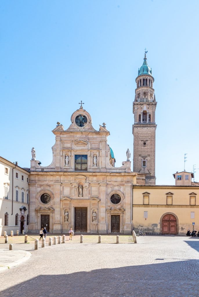 front facade of Church of San Giovanni Evangelista with bell tower behind it, one of the best things to do in parma italy