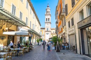 colorful street during a visit parma italy dead ending in a clock tower, historic center is one of the best things to do in parma