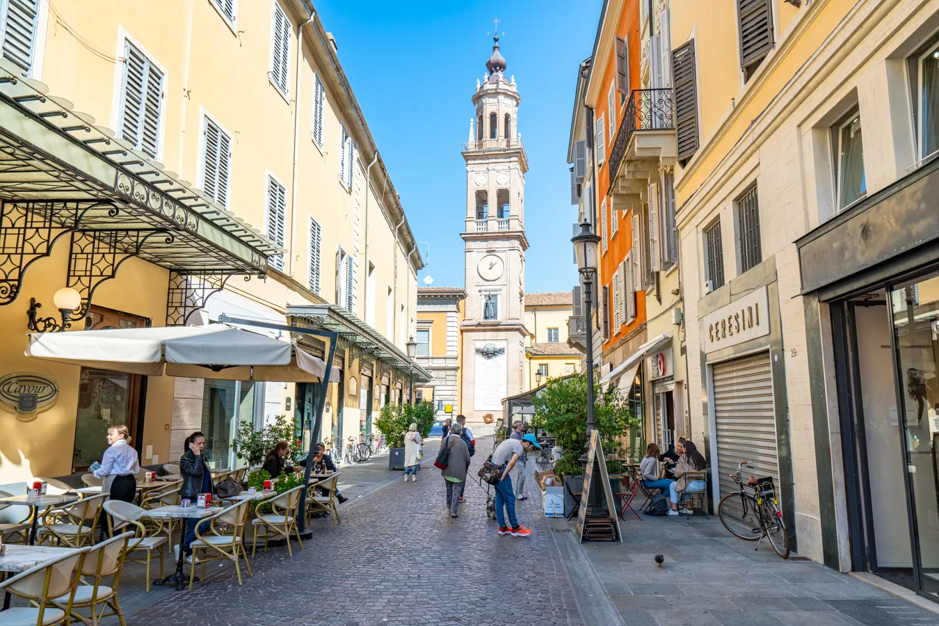 colorful street during a visit parma italy dead ending in a clock tower, historic center is one of the best things to do in parma