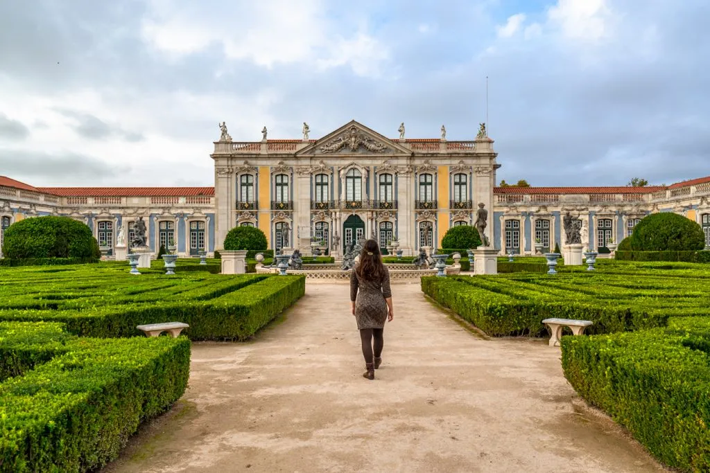 kate storm walking toward queluz national palace in the gardens