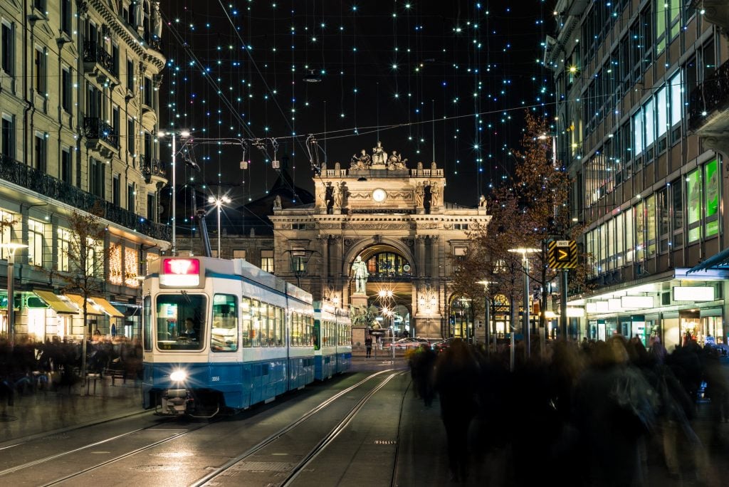 central zurich decorated for christmas at night with a tram running down the street