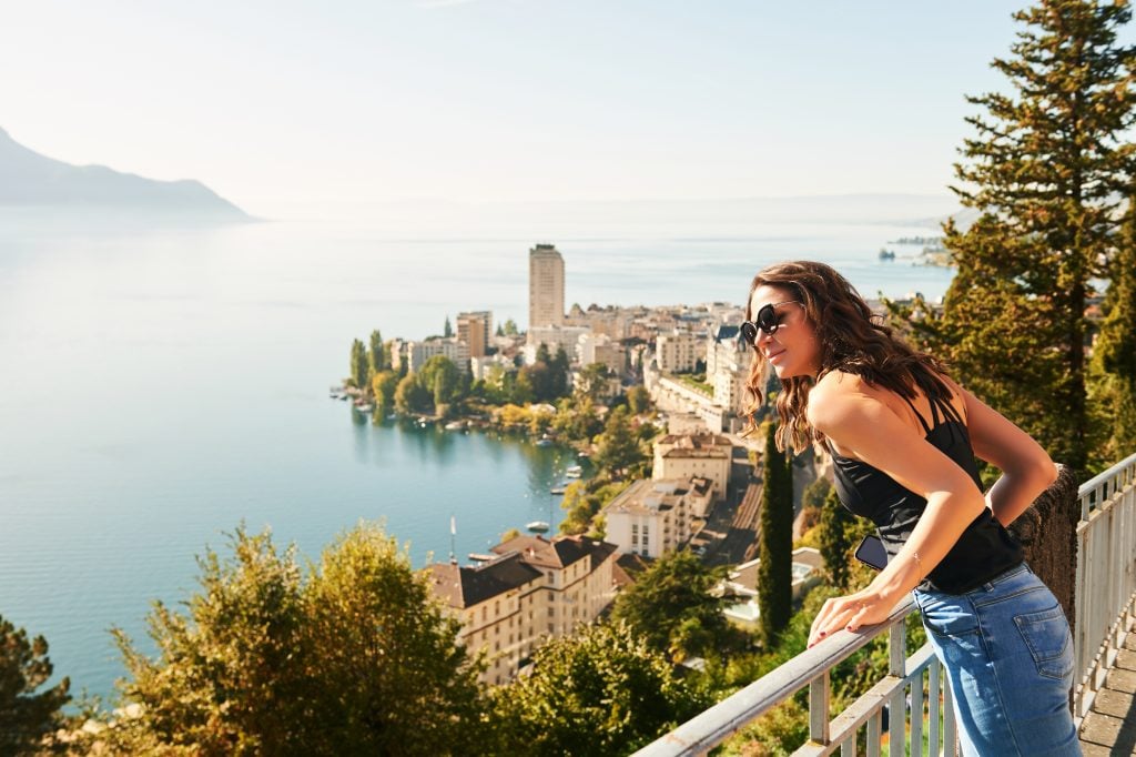 woman leaning over a rail overlooking montreux and lake geneva, some of the best places to visit in switzerland bucket list