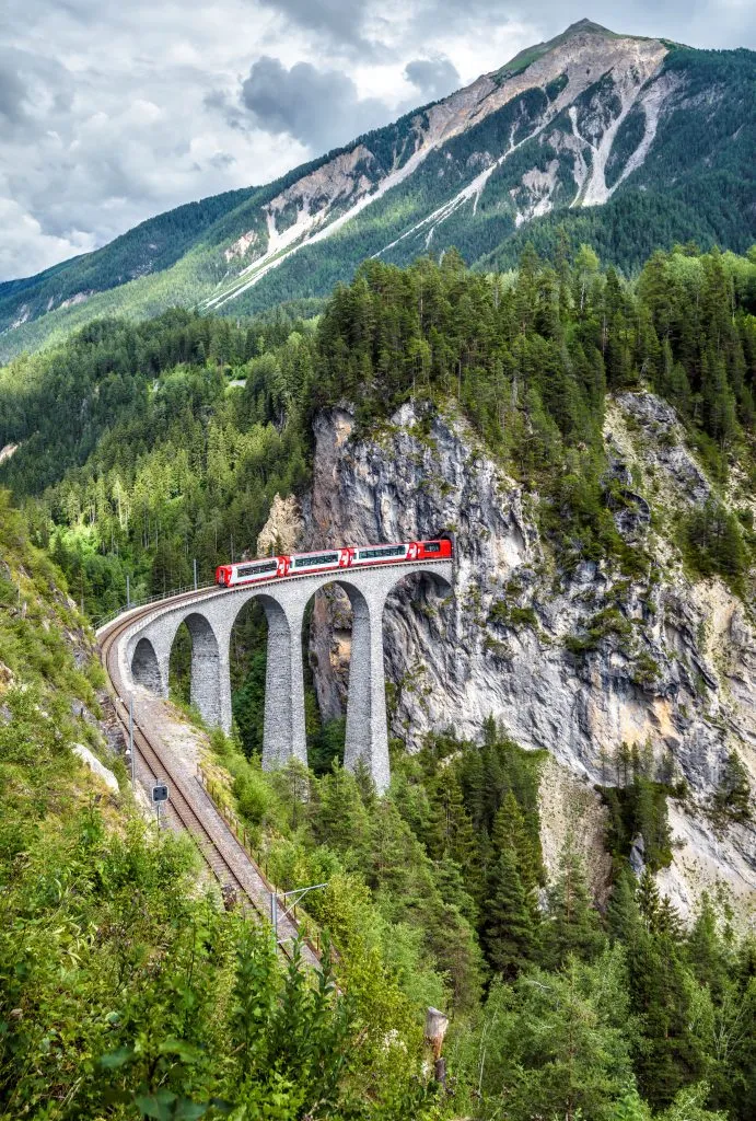 bernina express entering tunnel over landwasser viaduct, one of the most beautiful places in switzerland