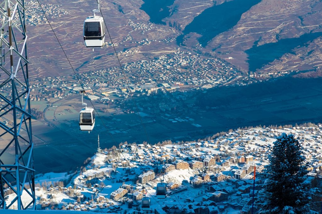 cable cars rising above nendaz, one of the best mountain towns in switzerland