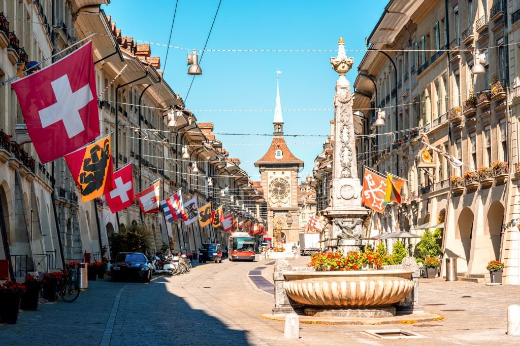 historic center of bern switzerland street lined with flags and clock tower in the distance