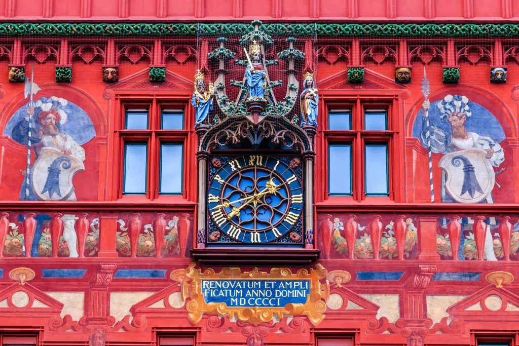 close up of red decor on basel town hall with clock in the center