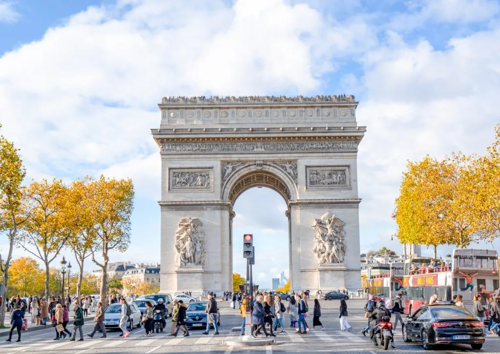 visit arc de triomphe paris france as seen from champs elysees with foliage on surrounding trees